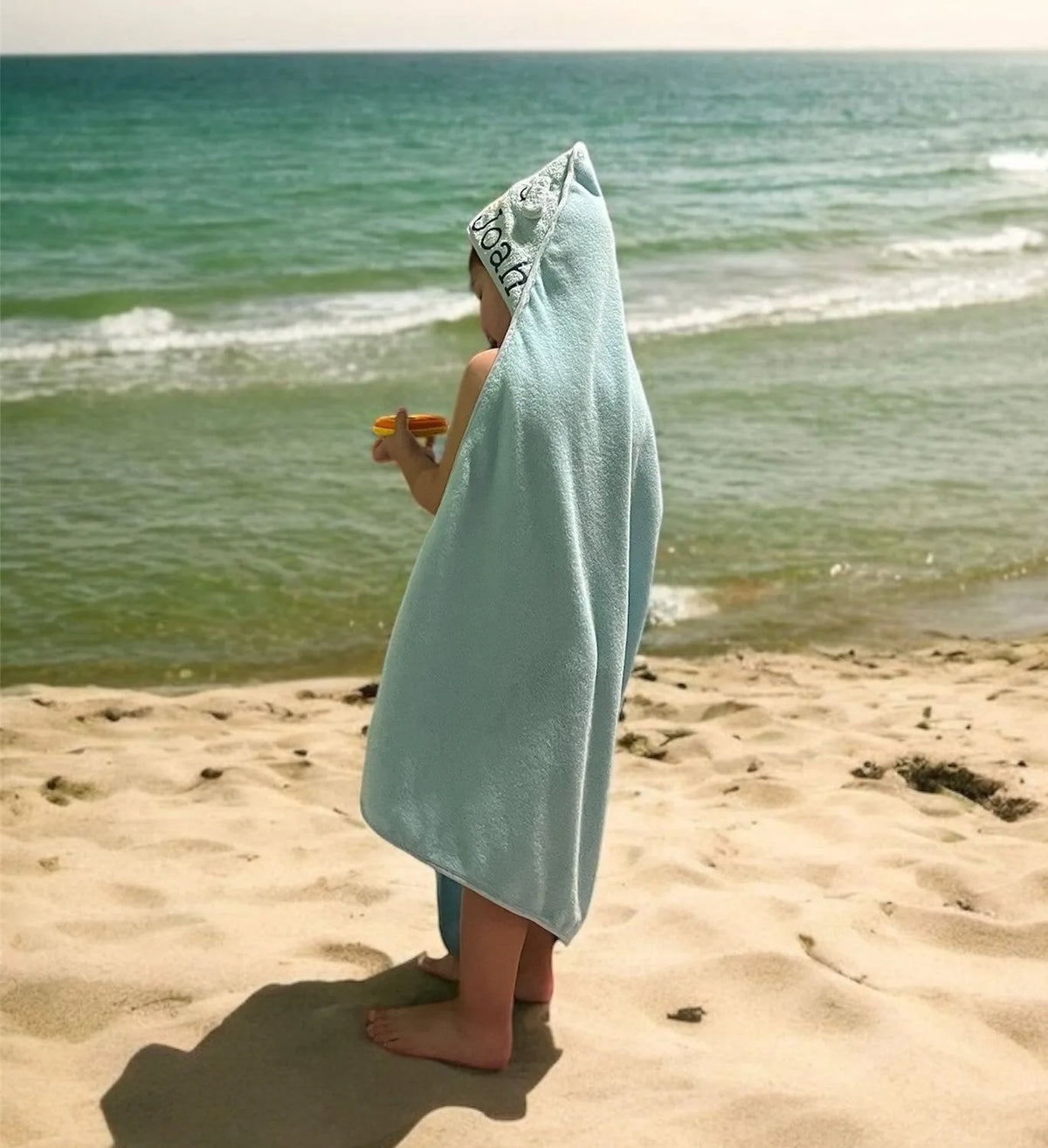 Kindje op het strand in een badcape